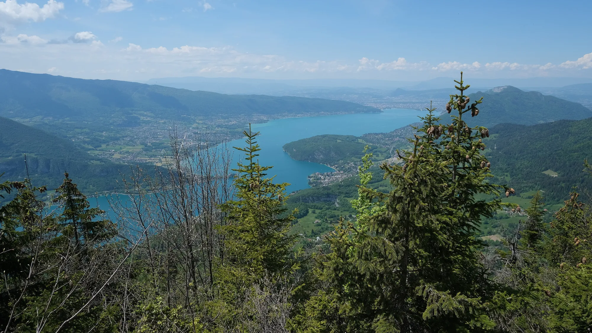 Le lac d’Annecy vu du Rocher du Roux, au-dessus de Talloires : l’eau turquoise, les villages du bord d’eau et les massifs qui ferment la vallée.